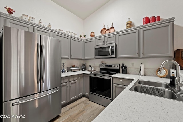 kitchen with light wood-style flooring, light countertops, stainless steel appliances, gray cabinetry, and a sink