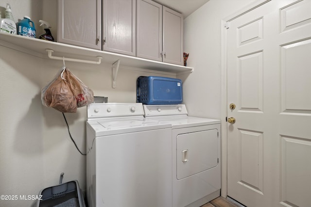 laundry area with independent washer and dryer and cabinet space