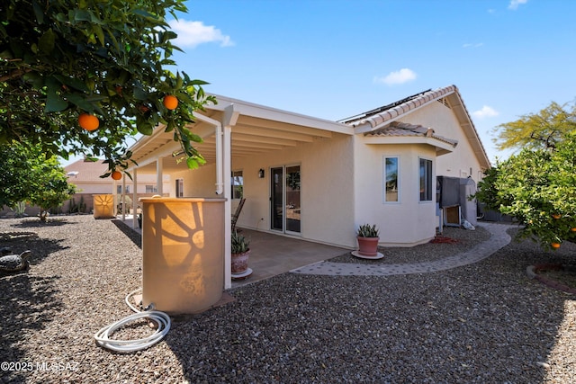 view of side of home featuring a patio, a tiled roof, and stucco siding