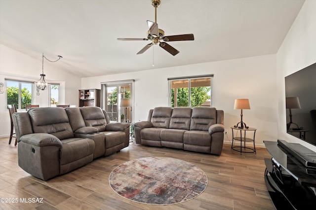 living area featuring a healthy amount of sunlight, baseboards, vaulted ceiling, and wood finished floors