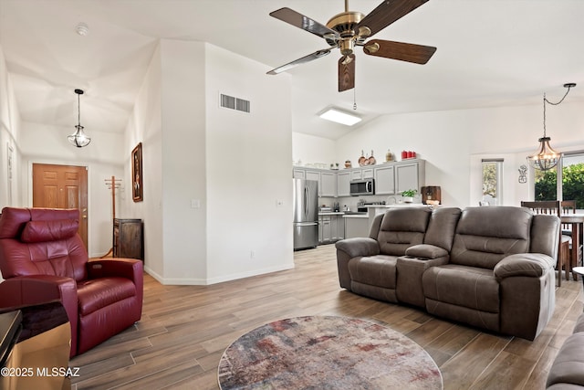 living room featuring light wood-style floors, baseboards, visible vents, and ceiling fan with notable chandelier