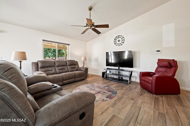 living area featuring baseboards, a ceiling fan, vaulted ceiling, and wood finished floors