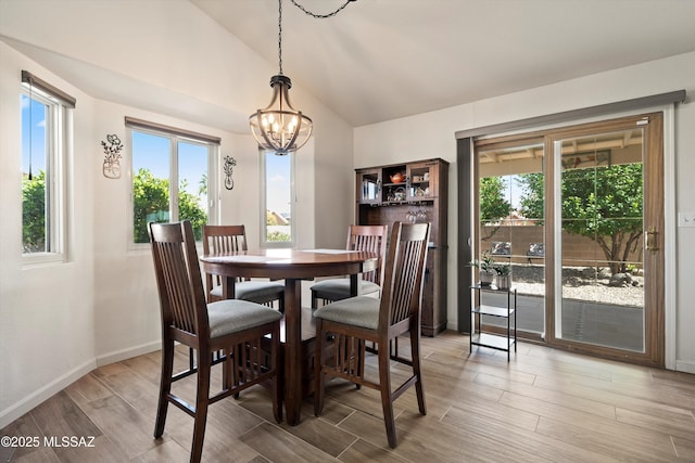 dining space featuring plenty of natural light, baseboards, vaulted ceiling, and wood finished floors