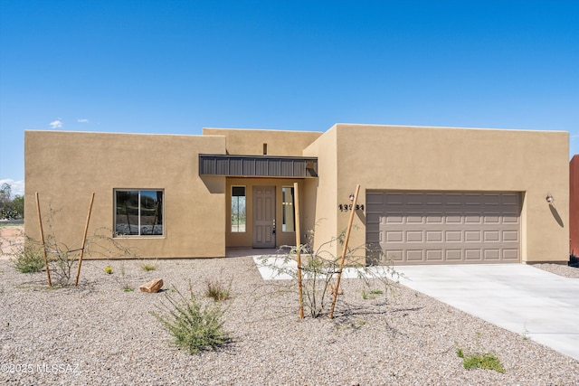 adobe home featuring stucco siding, concrete driveway, and a garage