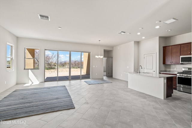 kitchen with visible vents, a chandelier, open floor plan, a center island with sink, and appliances with stainless steel finishes