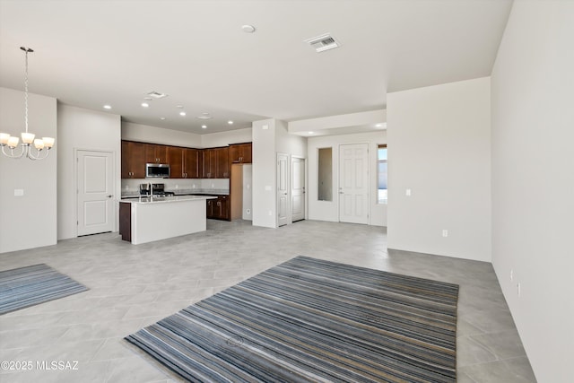 unfurnished living room featuring an inviting chandelier, recessed lighting, visible vents, and a sink