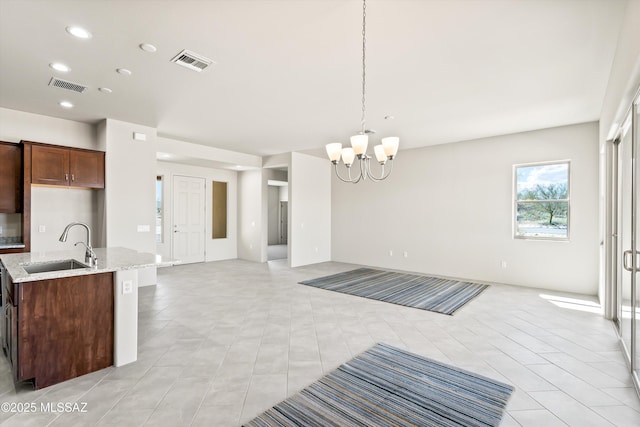 kitchen featuring a kitchen island with sink, visible vents, open floor plan, and a sink