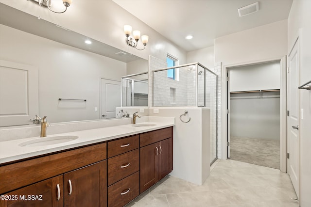 full bathroom featuring a shower stall, a spacious closet, double vanity, and a sink