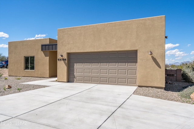 southwest-style home with a garage, driveway, and stucco siding