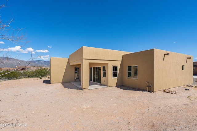 rear view of house with stucco siding, a patio, and a mountain view