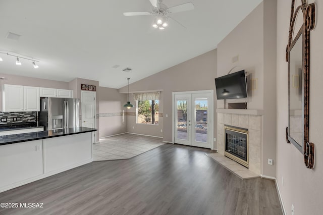 5481 W Cochie Springs St, Marana, AZ 85658 - kitchen featuring stainless steel refrigerator with ice dispenser, dark countertops, a ceiling fan, white cabinetry, and a tile fireplace