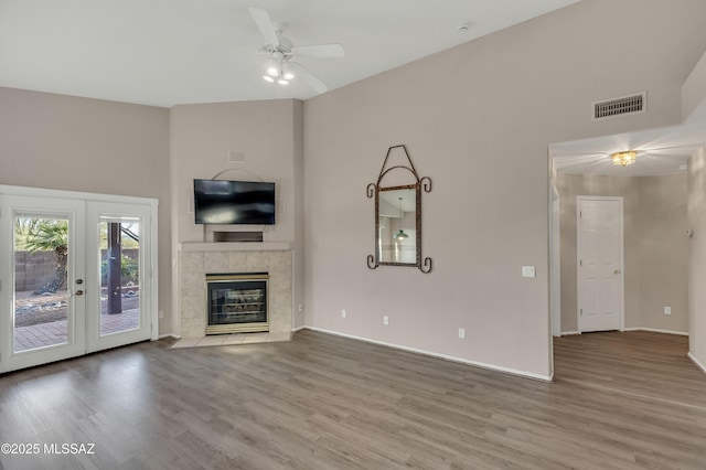 5481 W Cochie Springs St, Marana, AZ 85658 - unfurnished living room featuring baseboards, visible vents, ceiling fan, a tile fireplace, and wood finished floors