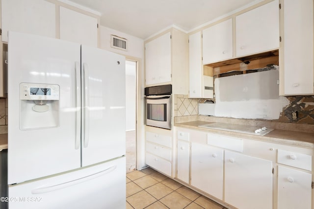 kitchen with light tile patterned floors, light countertops, visible vents, backsplash, and white appliances