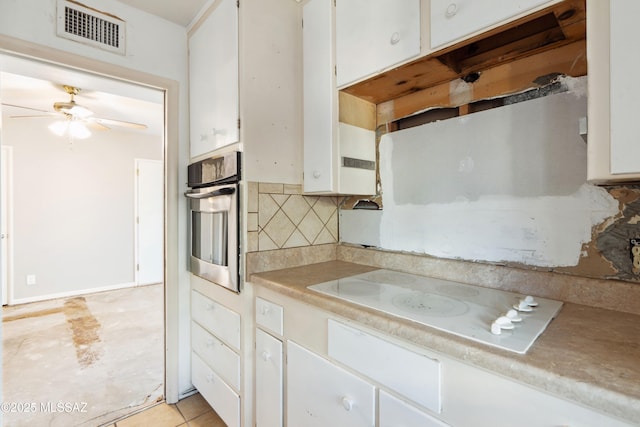 kitchen with white electric stovetop, tasteful backsplash, visible vents, white cabinetry, and oven