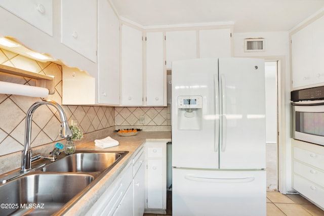 kitchen featuring a sink, visible vents, stainless steel oven, white cabinets, and white fridge with ice dispenser