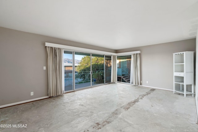 unfurnished room featuring baseboards and unfinished concrete floors