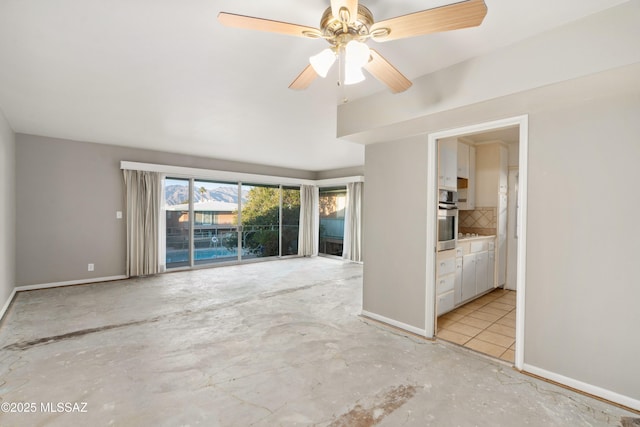 spare room with baseboards and a ceiling fan