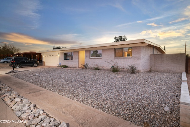 ranch-style home with brick siding, driveway, an attached garage, and fence