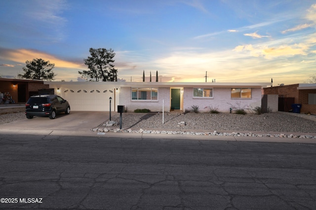 single story home with brick siding, driveway, and an attached garage