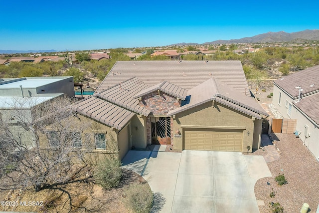 view of front of home featuring a garage, stucco siding, a mountain view, and a tiled roof