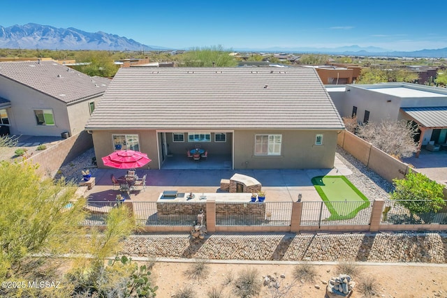 exterior space with a patio, a fenced backyard, a tile roof, a mountain view, and stucco siding