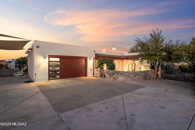 view of front of house featuring a garage, driveway, fence, and stucco siding