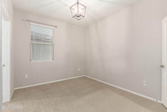 carpeted spare room with a chandelier