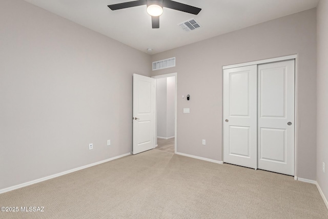 unfurnished bedroom with light colored carpet, ceiling fan, and a closet