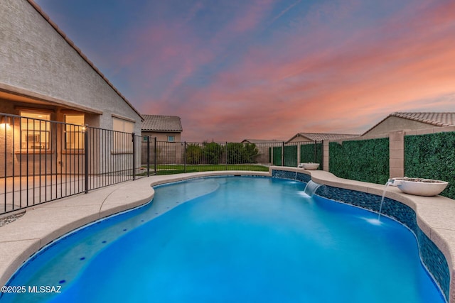 pool at dusk featuring pool water feature