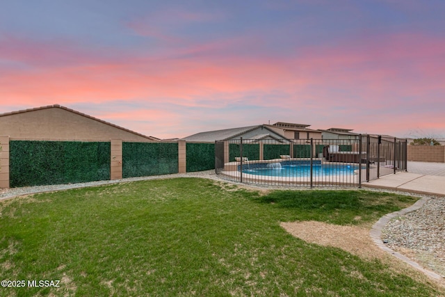 pool at dusk featuring a patio area and a lawn