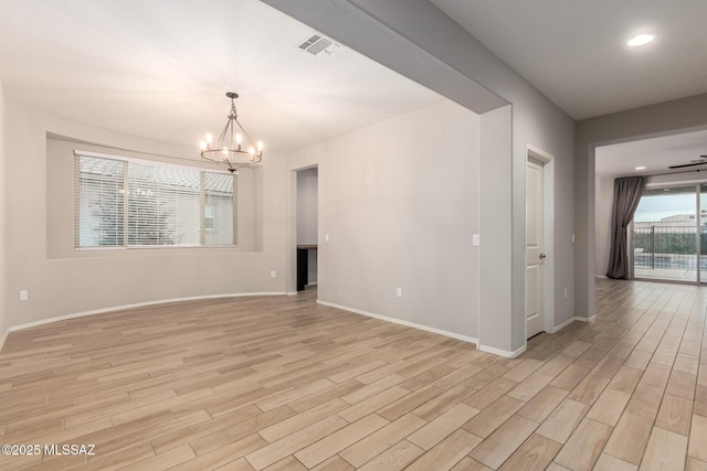 spare room with an inviting chandelier and light wood-type flooring