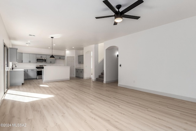 unfurnished living room featuring ceiling fan, sink, and light wood-type flooring