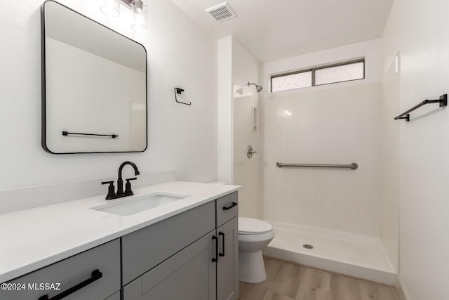 bathroom with vanity, a shower, hardwood / wood-style floors, and toilet