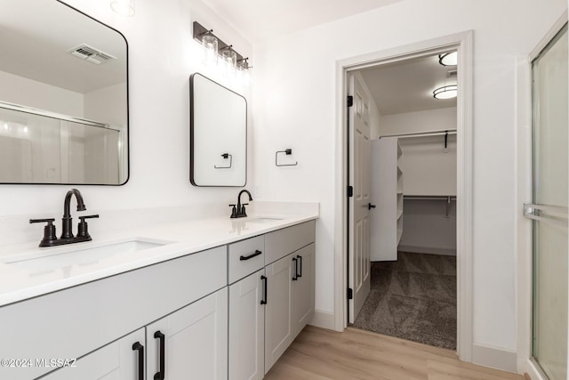 bathroom with hardwood / wood-style flooring, vanity, and a shower with shower door