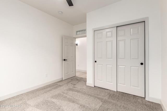 unfurnished bedroom with ceiling fan, a closet, and light carpet