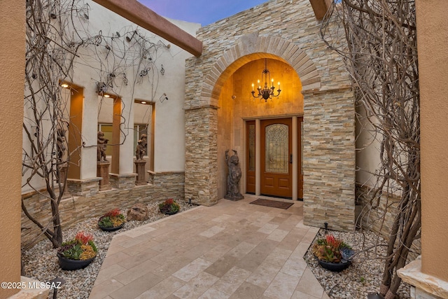 view of exterior entry featuring stone siding and stucco siding