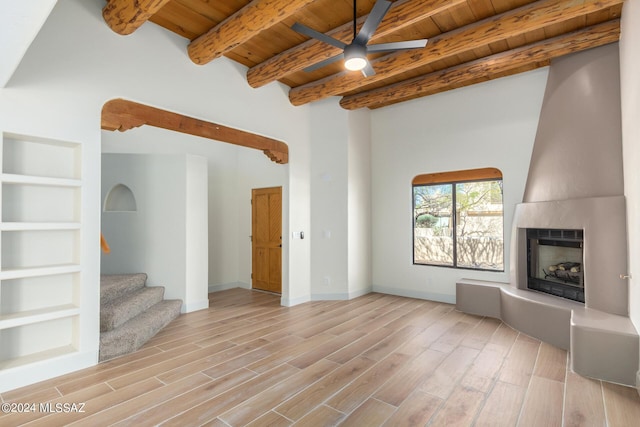 unfurnished living room with a fireplace, light hardwood / wood-style floors, beam ceiling, and wooden ceiling