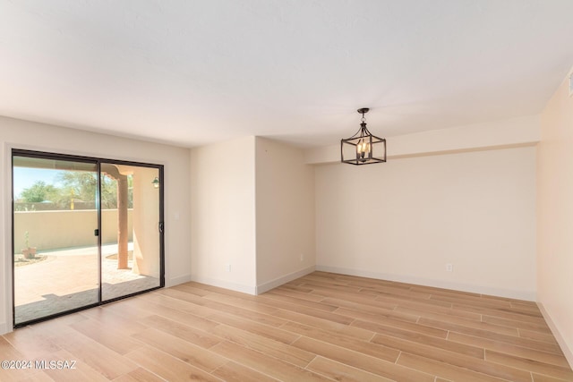 empty room featuring an inviting chandelier and light hardwood / wood-style flooring