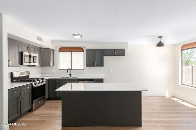 kitchen with pendant lighting, sink, stainless steel appliances, and a kitchen island