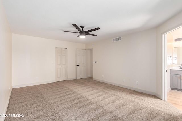 unfurnished bedroom featuring ceiling fan, connected bathroom, and light carpet