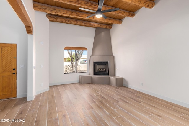 unfurnished living room featuring beamed ceiling, a large fireplace, wooden ceiling, and light hardwood / wood-style flooring