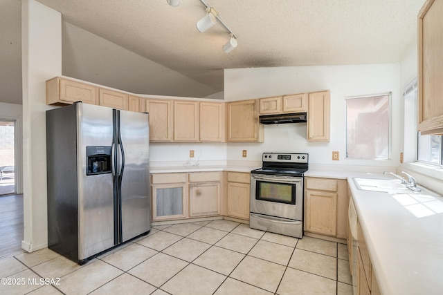 kitchen featuring vaulted ceiling, sink, light tile patterned floors, stainless steel appliances, and light brown cabinets