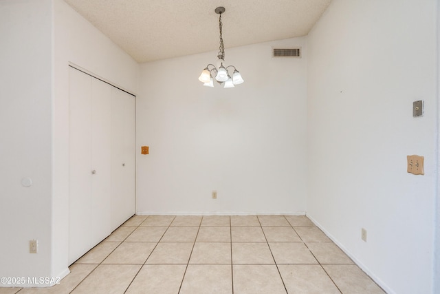 unfurnished dining area featuring an inviting chandelier, vaulted ceiling, and a textured ceiling