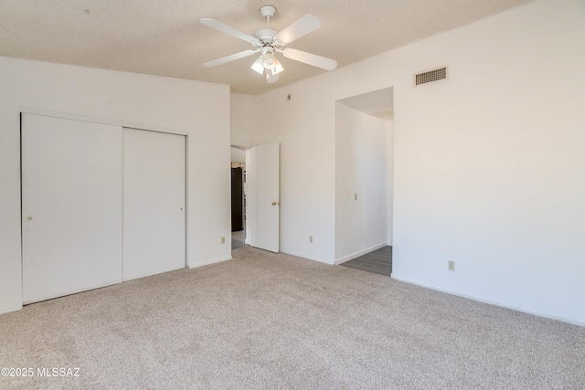 unfurnished bedroom with ceiling fan, a closet, a textured ceiling, and carpet flooring