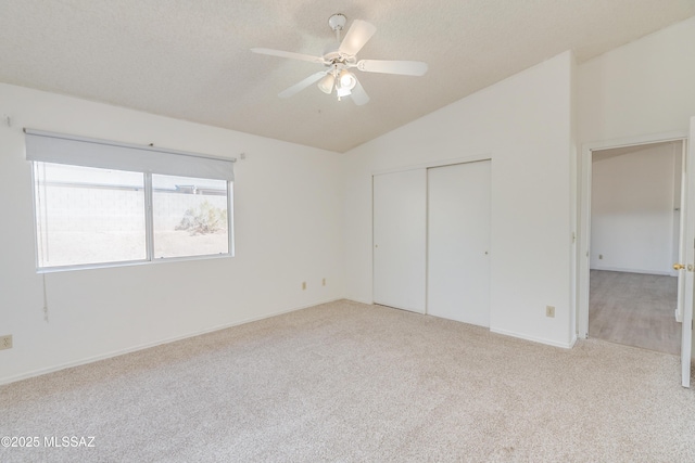 unfurnished bedroom with lofted ceiling, ceiling fan, a textured ceiling, light carpet, and a closet