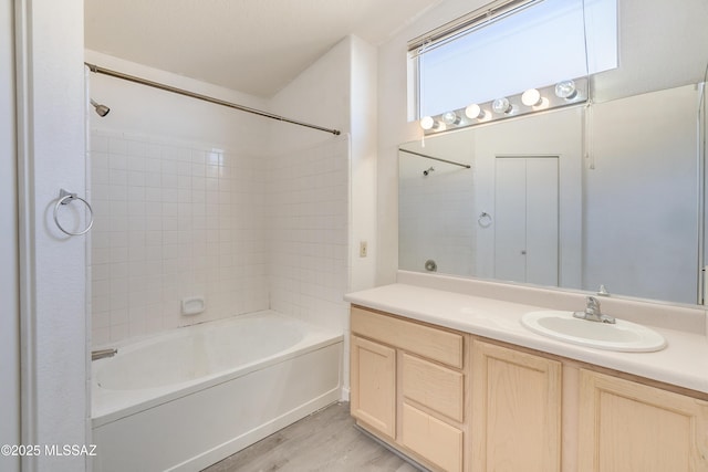 bathroom with vanity, hardwood / wood-style flooring, and tiled shower / bath