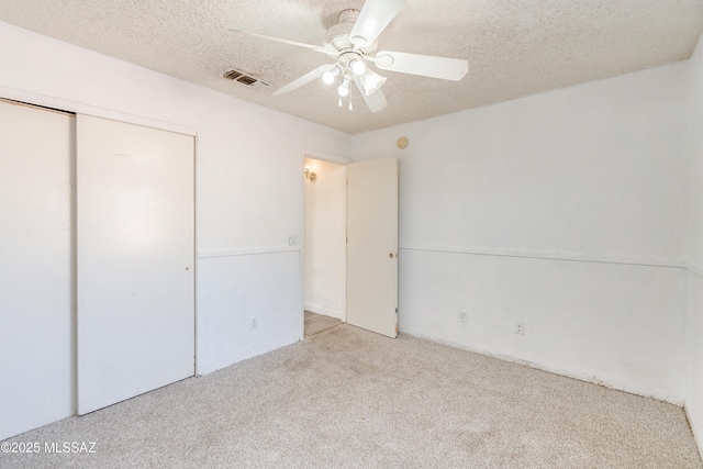 unfurnished bedroom with ceiling fan, light carpet, a textured ceiling, and a closet