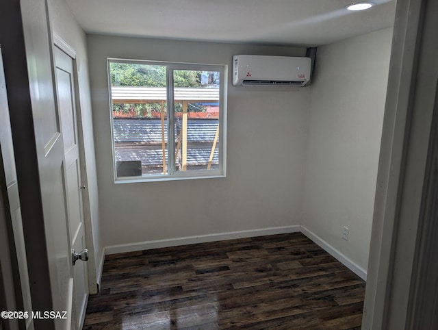 unfurnished room featuring an AC wall unit, dark wood-style flooring, and baseboards