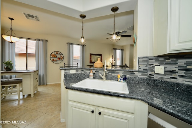 kitchen with hanging light fixtures, sink, dark stone countertops, and decorative backsplash