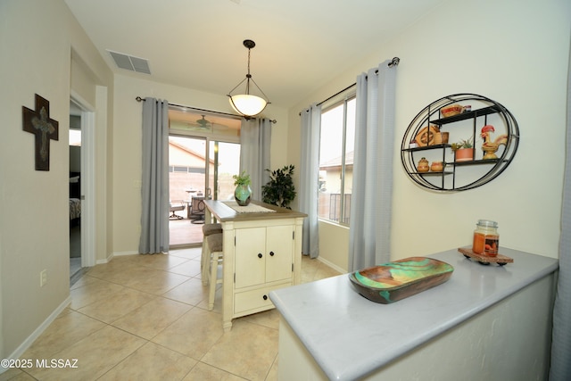 interior space with light tile patterned floors, decorative light fixtures, kitchen peninsula, and a kitchen island